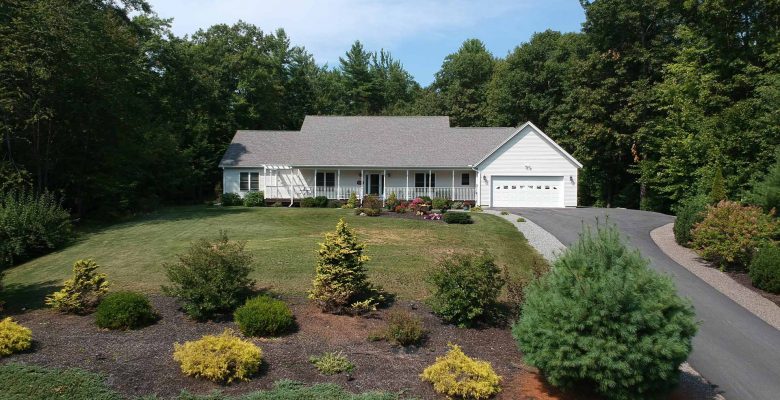 Aerial shot of house with a well-landscaped yard and asphalt driveway