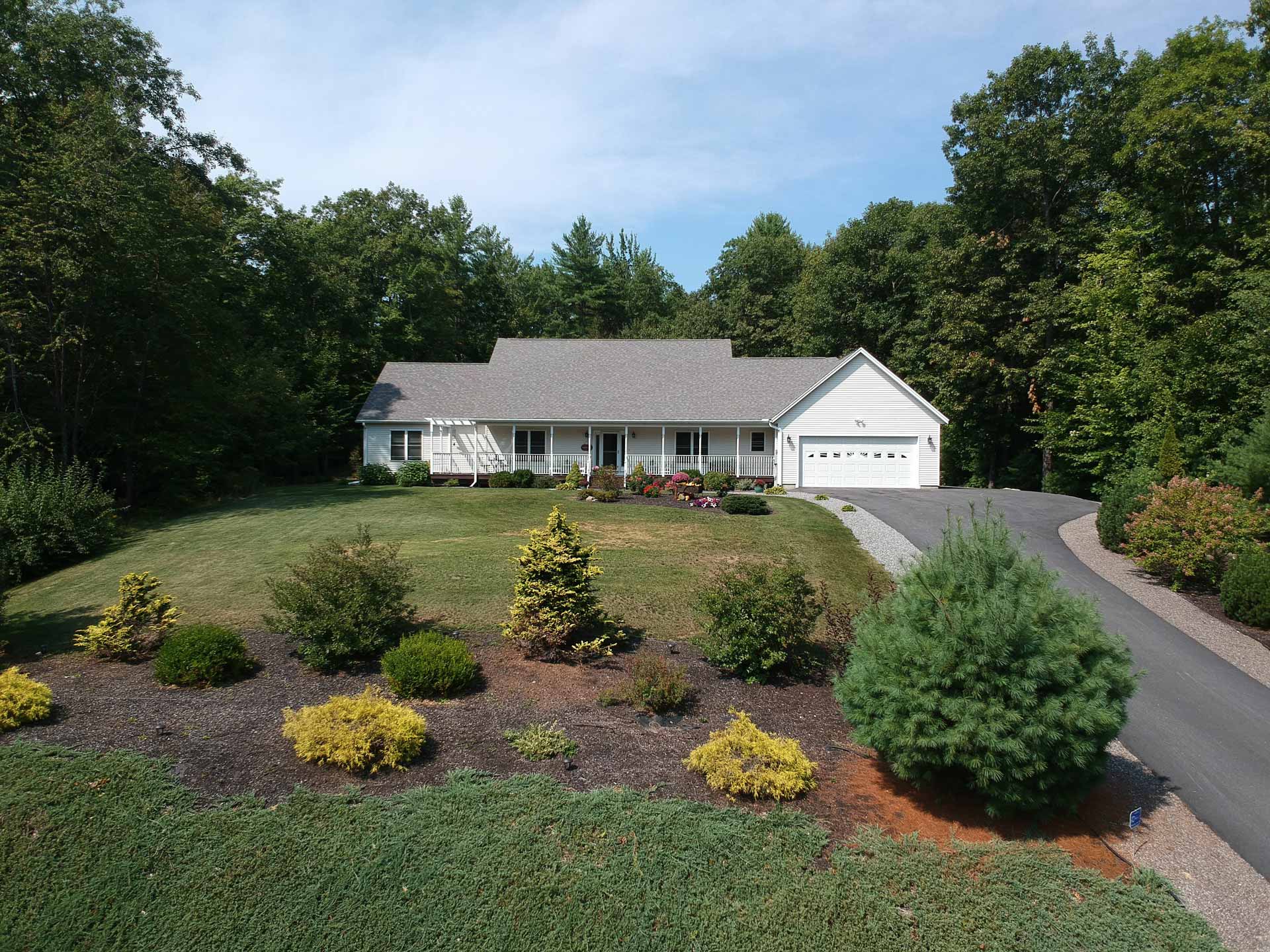 Aerial shot of house with a well-landscaped yard and asphalt driveway